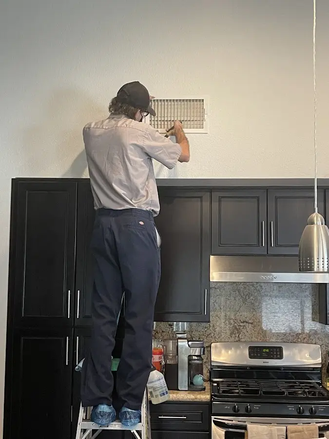 Technician inspecting an air vent during HVAC service in Vernal
